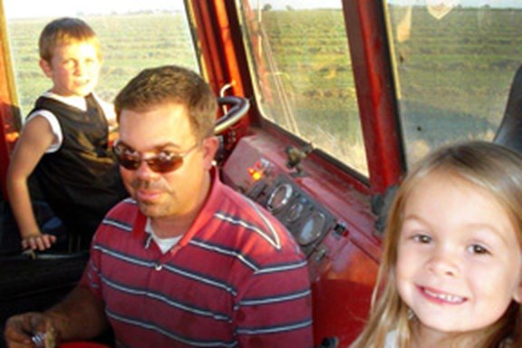 Bryan Mello with his children in a tractor cab