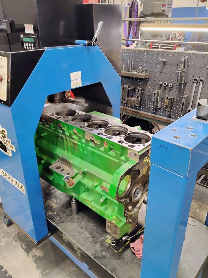 A green tractor engine block clamped in the surfacing machine
