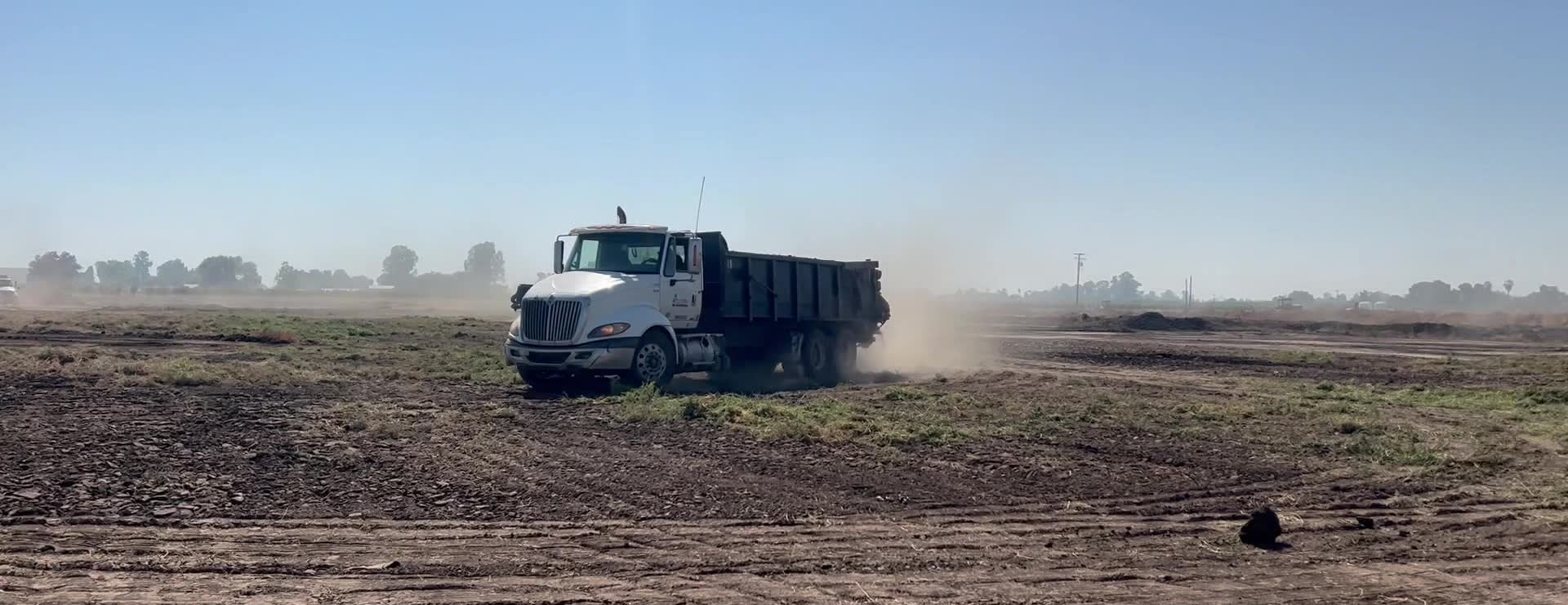 A B. Mello spreader truck laying woodchips across an open field